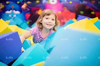 Little girl playing in colorful soft foam block sensory play zone, safe indoor kids playground sensory activity area for family entertainment center