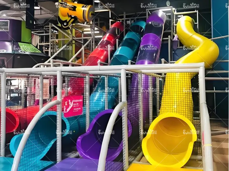 Indoor playground multi-color spiral tube slides with red, cyan, purple and yellow plastic tunnels surrounded by safety netting