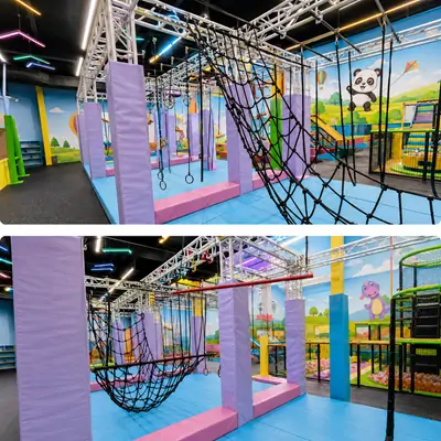 Indoor ninja warrior obstacle course at Little Champs Playland equipped with climbing nets, hanging rings, padded support pillars and colorful cartoon animal wall murals for kids physical activity